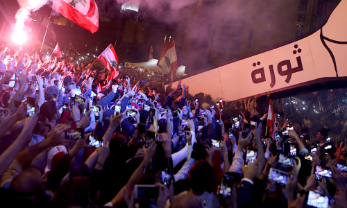 Lebanese demonstrators raise a giant sign of a fist that bears the Arabic word "revolution" on it in the Lebanese capital Beirut's Martyr's Square in November 2019 